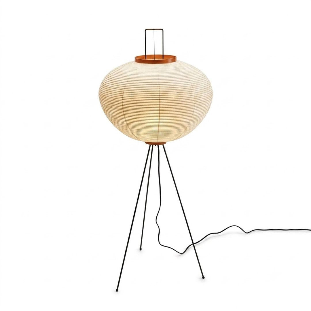Stuber Lighting Akari 10A Japanese rice paper standing lamp glowing with warm light, black tripod base, isolated on a clean studio background.