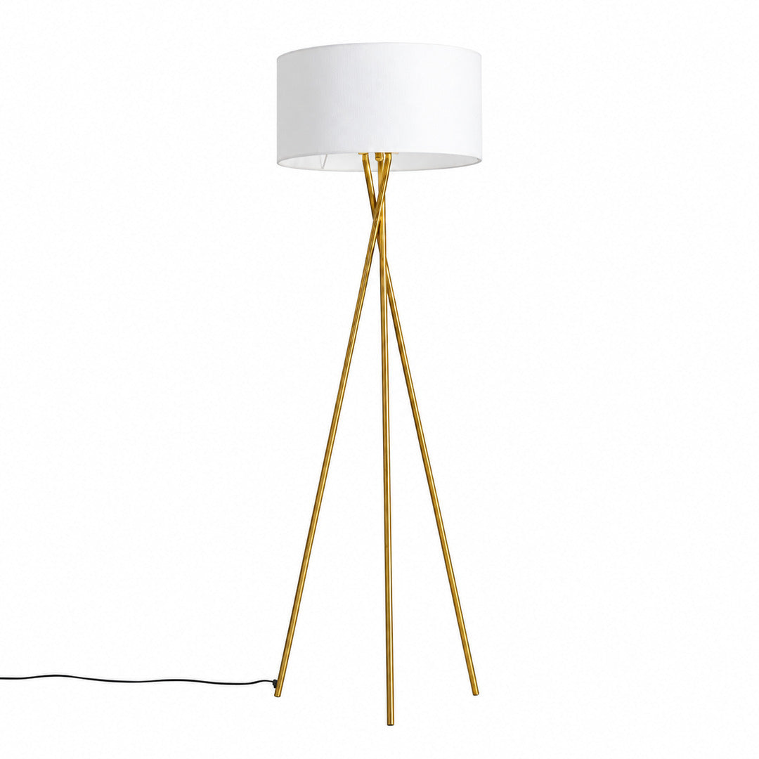 Grazia gold tripod floor lamp with a white fabric shade standing beside a modern sofa