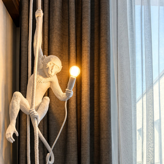 Close-up of the detailed resin monkey sculpture holding a bulb on the Monkey pendant light