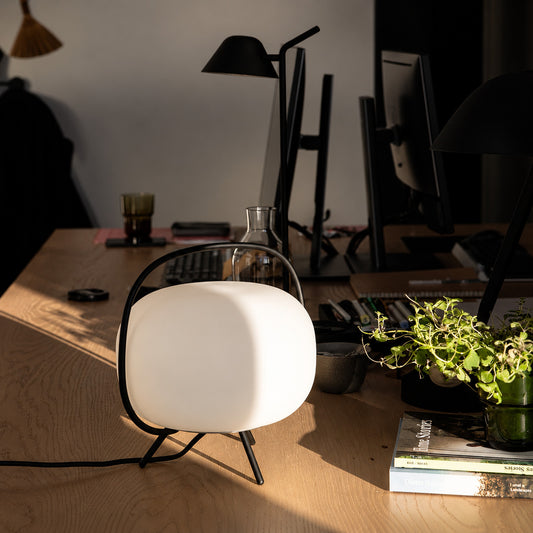 Nomade glass table lamp adding a soft warm glow to a home office desk