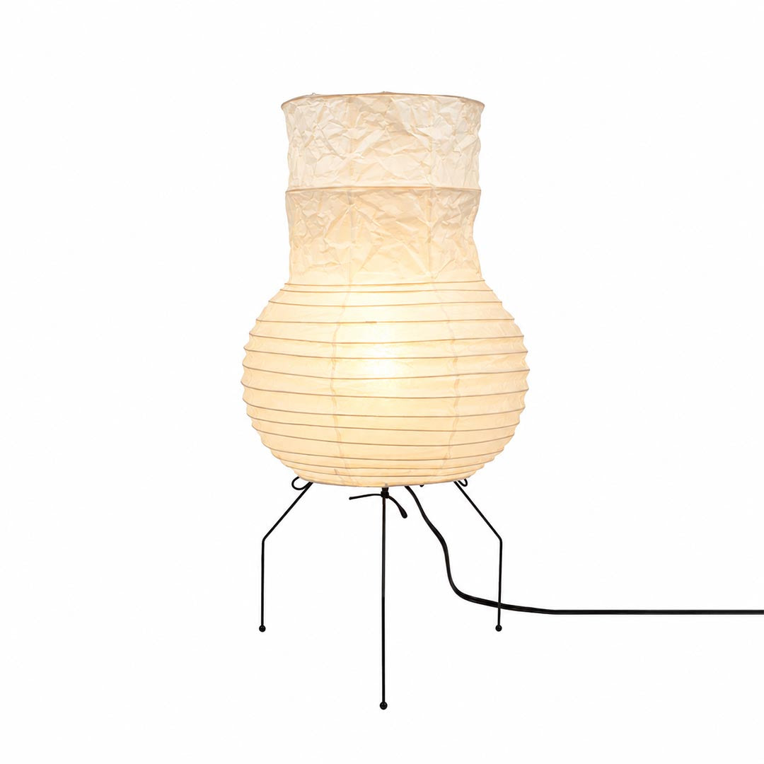 Warmly glowing vase-shaped Washi Paper Zara Table Lamp with a tripod wire base against a white background by Stuber Lighting.