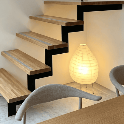 Large 22N Washi paper table lamp with bamboo ribs, glowing warmly on a minimalist floor setting.
