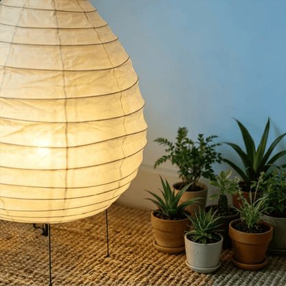 Large 22N Washi paper table lamp with bamboo ribs, glowing warmly on a minimalist floor setting.