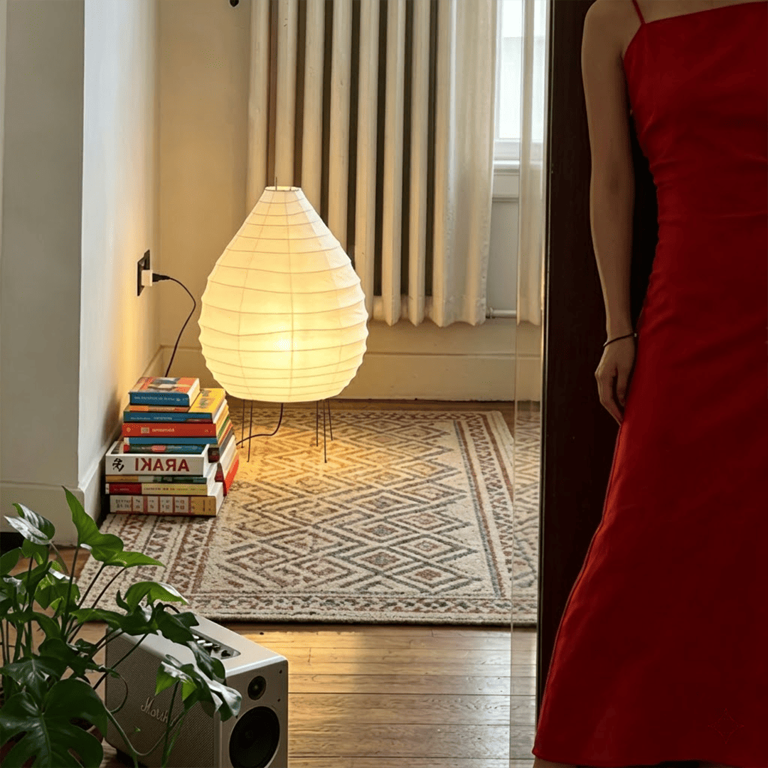 Large 22N Washi paper table lamp with bamboo ribs, glowing warmly on a minimalist floor setting.