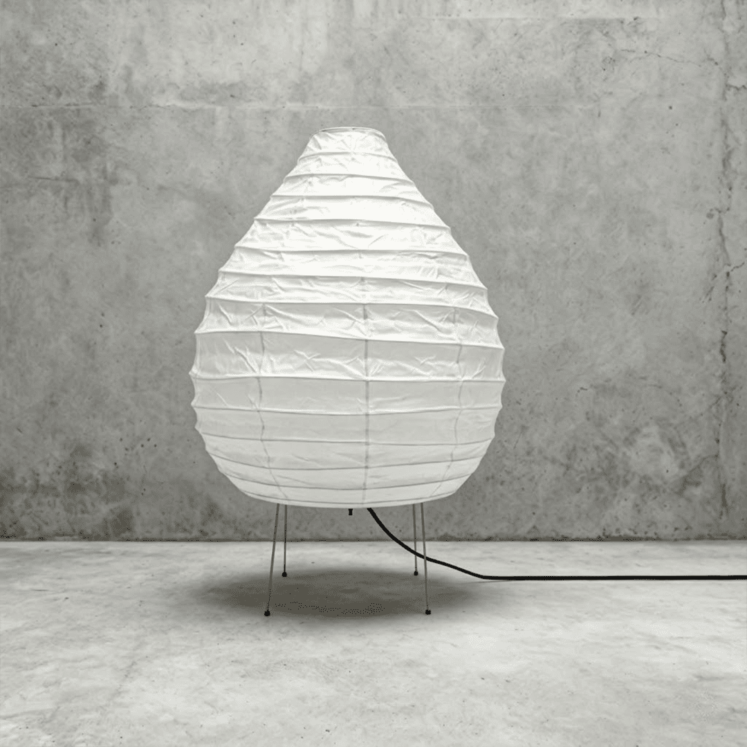 Large 22N Washi paper table lamp with bamboo ribs, glowing warmly on a minimalist floor setting.