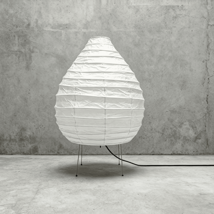 Large 22N Washi paper table lamp with bamboo ribs, glowing warmly on a minimalist floor setting.
