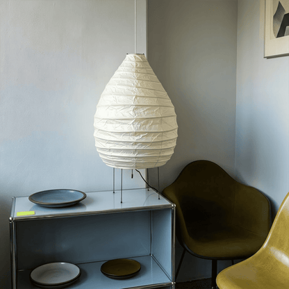 Large 22N Washi paper table lamp with bamboo ribs, glowing warmly on a minimalist floor setting.