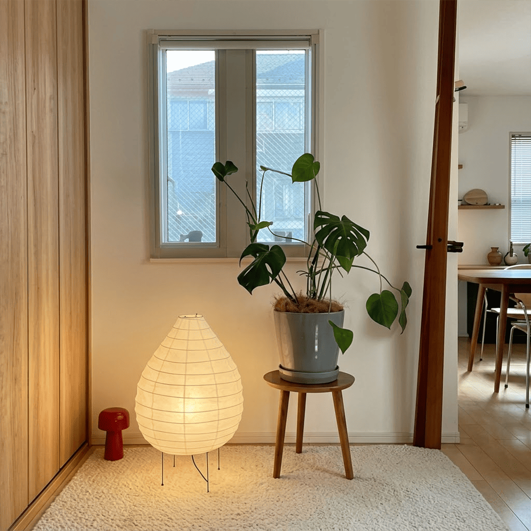 Large 22N Washi paper table lamp with bamboo ribs, glowing warmly on a minimalist floor setting.