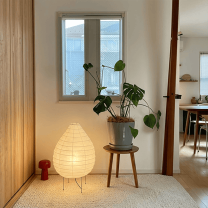 Large 22N Washi paper table lamp with bamboo ribs, glowing warmly on a minimalist floor setting.