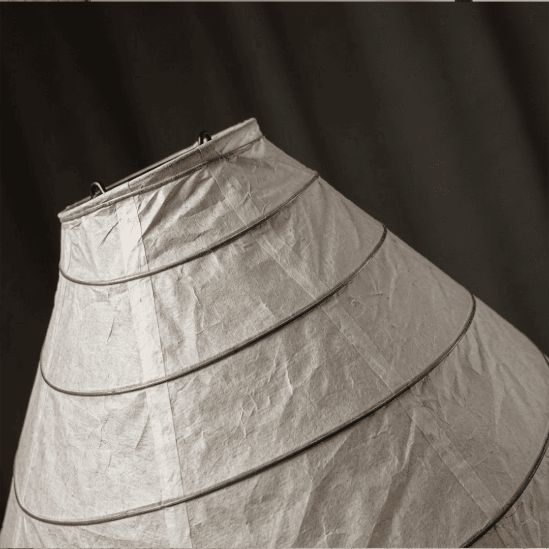 Large 22N Washi paper table lamp with bamboo ribs, glowing warmly on a minimalist floor setting.