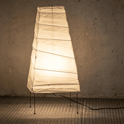 Handcrafted organic oval Washi Paper 4N Table Lamp on black tripod legs emitting a soft warm glow in a Japandi style interior setting.