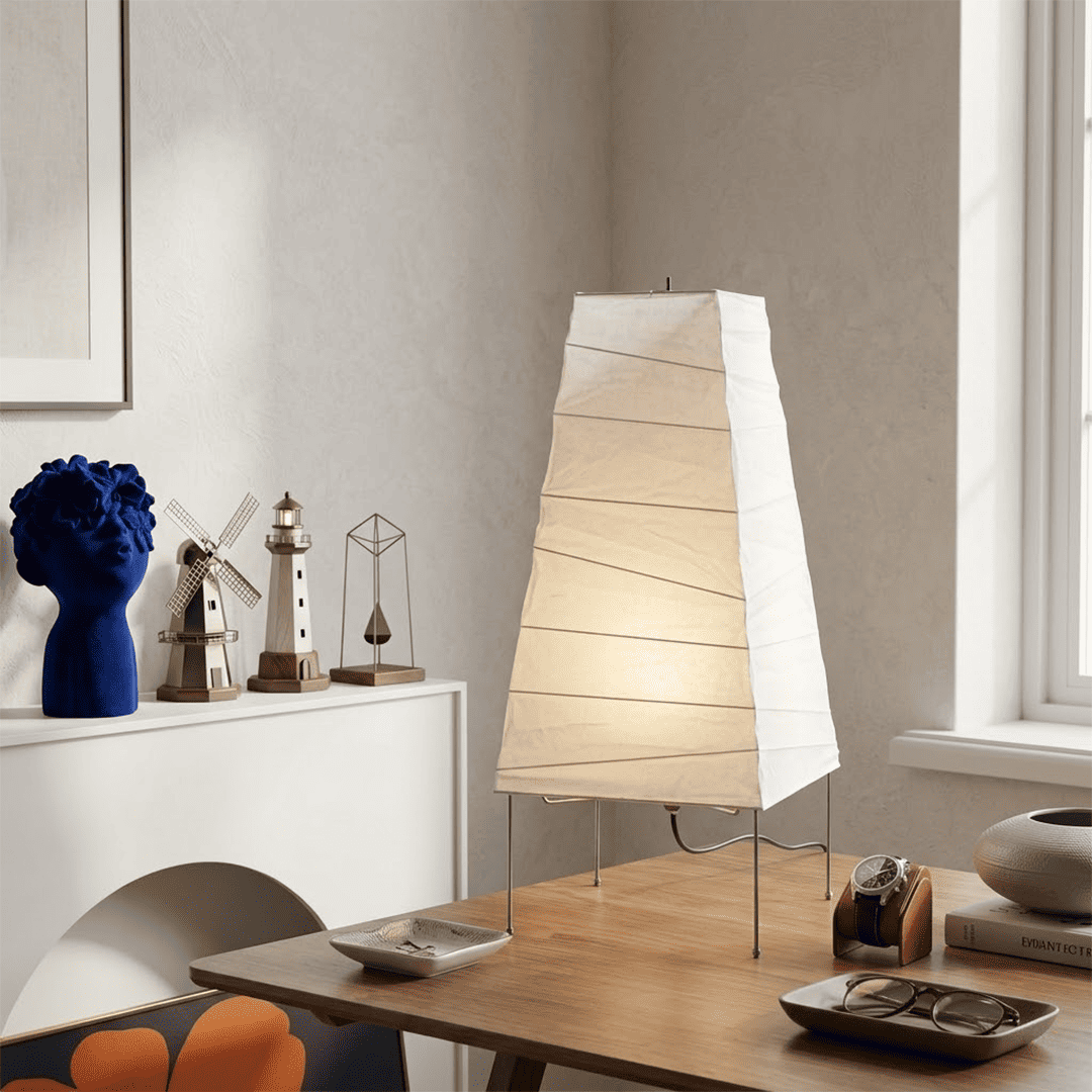 Handcrafted organic oval Washi Paper 4N Table Lamp on black tripod legs emitting a soft warm glow in a Japandi style interior setting.