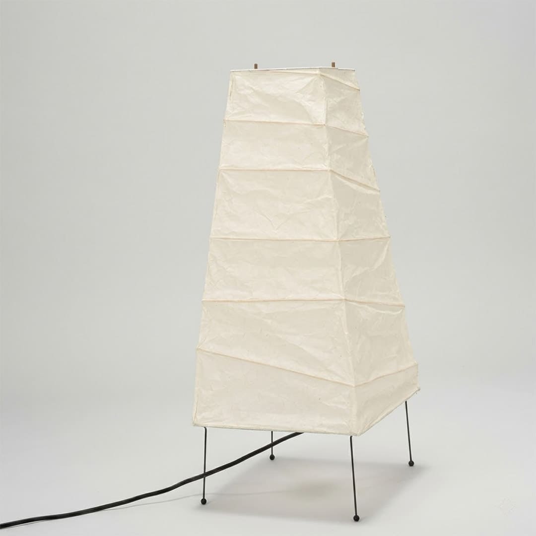 Handcrafted organic oval Washi Paper 4N Table Lamp on black tripod legs emitting a soft warm glow in a Japandi style interior setting.