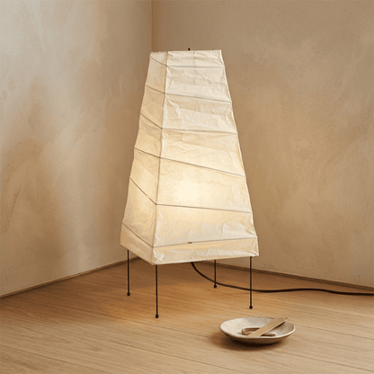 Handcrafted organic oval Washi Paper 4N Table Lamp on black tripod legs emitting a soft warm glow in a Japandi style interior setting.