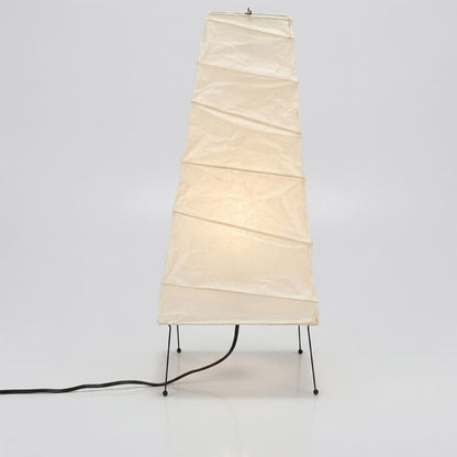 Handcrafted organic oval Washi Paper 4N Table Lamp on black tripod legs emitting a soft warm glow in a Japandi style interior setting.