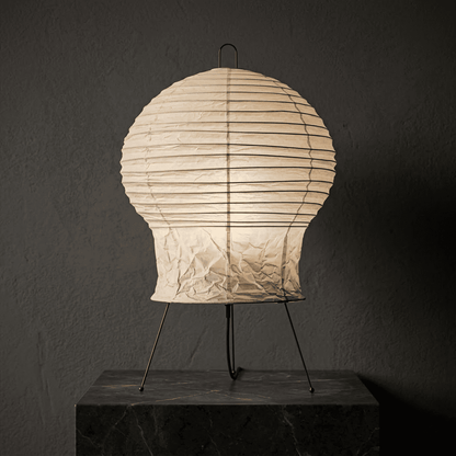 Akari 2N Table Lamp handmade with mulberry paper on a minimalist tripod stand, warm light glowing through textured washi paper.
