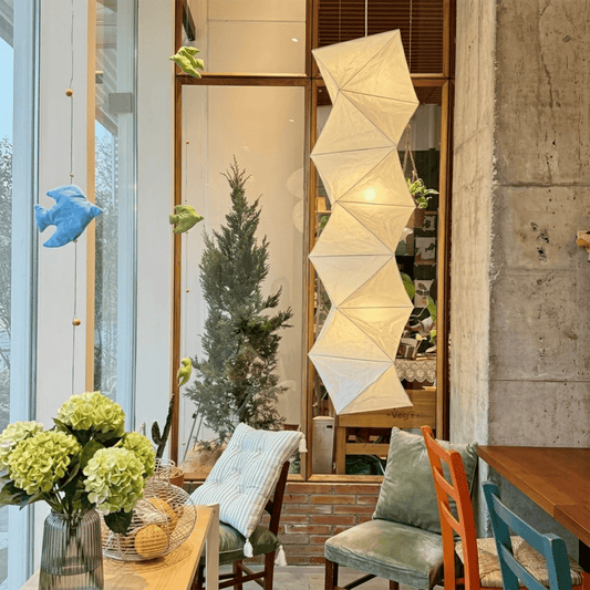 Large Akari L8 style vertical washi paper pendant light, 63 inches tall with accordion folds, emitting a warm ethereal glow.