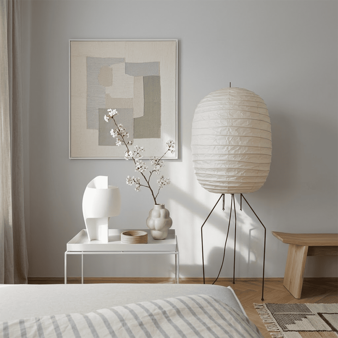 Large Akari UF3-DL floor lamp with a white washi paper shade on a black tripod metal stand, glowing with warm light in a minimalist room.