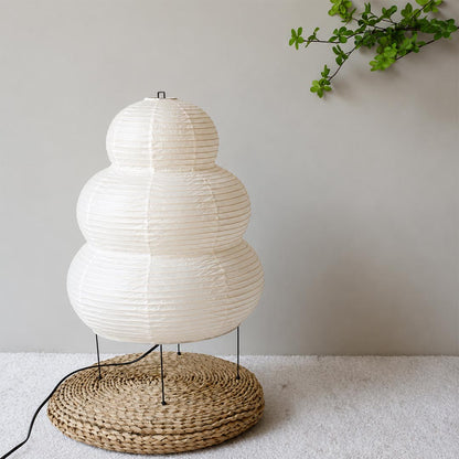 Close-up of the unlit, texturized crinkled paper shade of the Washi Paper 25N Table Lamp on a woven rattan mat by Stuber Lighting.