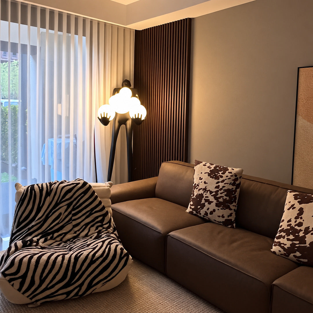 Abbraccio glass floor lamp standing beside a sofa as a sculptural centerpiece in a living room