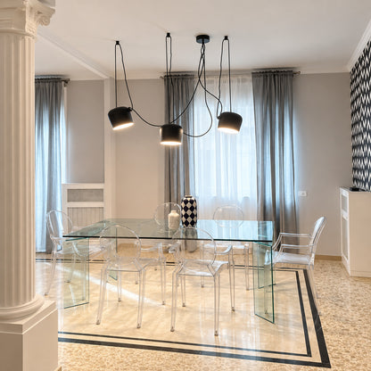Aim pendant light casting adjustable warm light over a contemporary dining table
