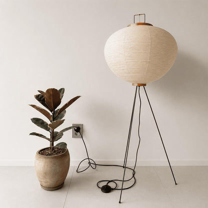Stuber Lighting tripod paper lantern floor light surrounded by green houseplants, creating a relaxing Wabi-Sabi corner at twilight.