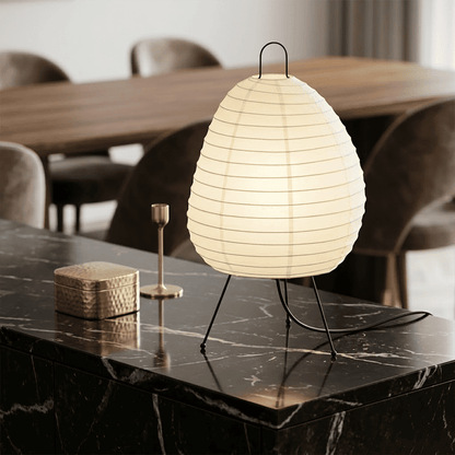 Premium Akari 1N washi paper table lamp emitting a warm glow on a wooden desk.