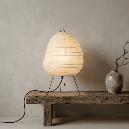 Premium Akari 1N washi paper table lamp emitting a warm glow on a wooden desk.