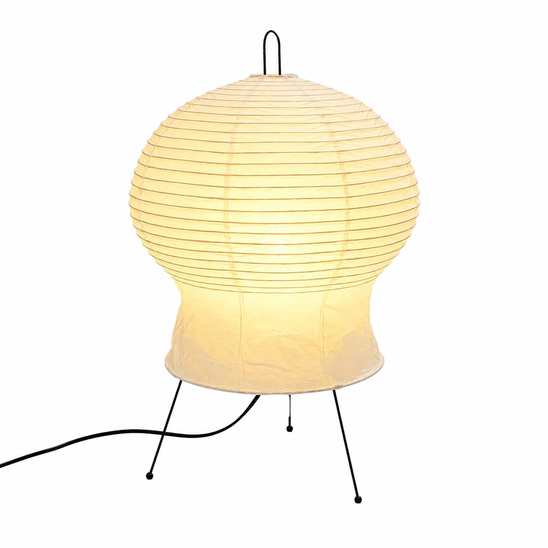 Illuminated Akari 2N Table Lamp with a ribbed paper shade glowing warmly against a white background by Stuber Lighting.