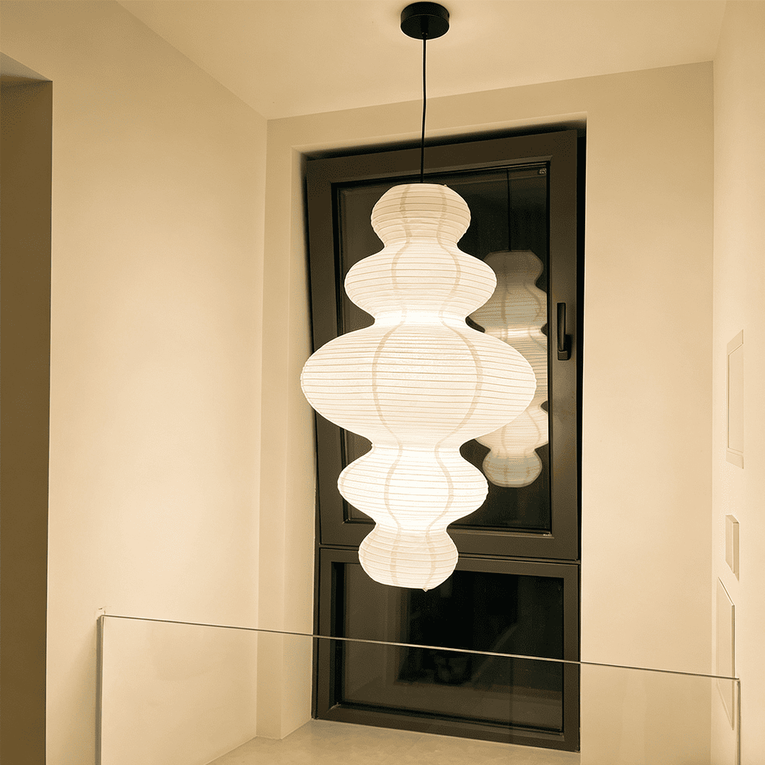 Large Akari Juni washi paper pendant lamp glowing in a minimalist Japandi living room with warm 3000K light.