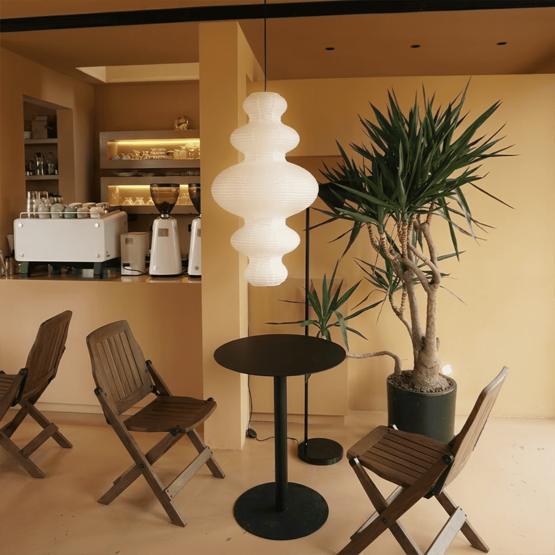 Large Akari Juni washi paper pendant lamp glowing in a minimalist Japandi living room with warm 3000K light.