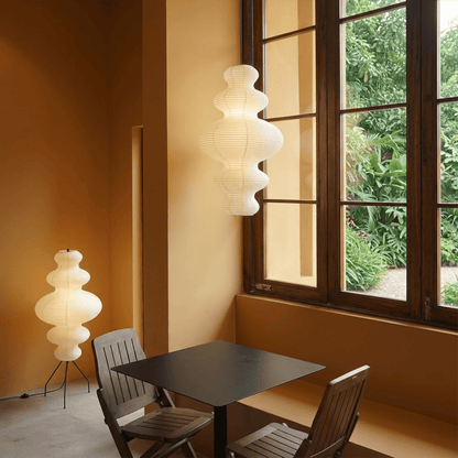 Large Akari Juni washi paper pendant lamp glowing in a minimalist Japandi living room with warm 3000K light.
