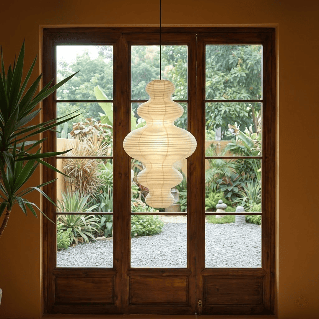 Large Akari Juni washi paper pendant lamp glowing in a minimalist Japandi living room with warm 3000K light.