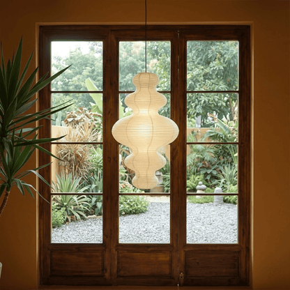 Large Akari Juni washi paper pendant lamp glowing in a minimalist Japandi living room with warm 3000K light.