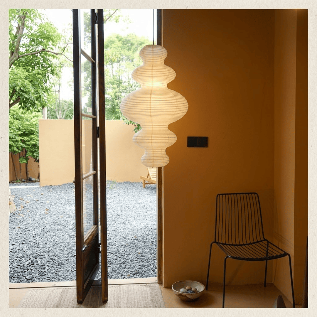 Large Akari Juni washi paper pendant lamp glowing in a minimalist Japandi living room with warm 3000K light.
