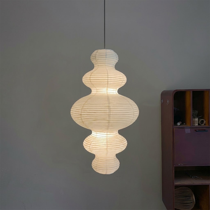 Large Akari Juni washi paper pendant lamp glowing in a minimalist Japandi living room with warm 3000K light.