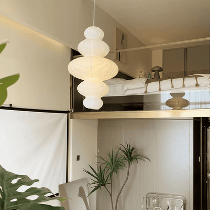 Large Akari Juni washi paper pendant lamp glowing in a minimalist Japandi living room with warm 3000K light.