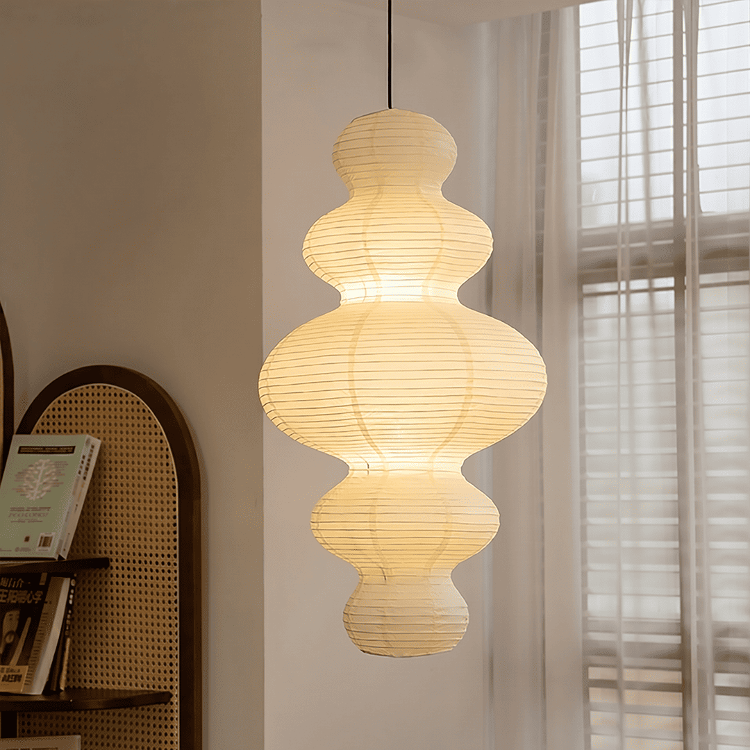 Large Akari Juni washi paper pendant lamp glowing in a minimalist Japandi living room with warm 3000K light.