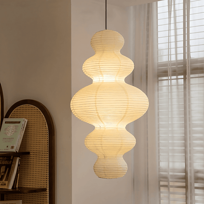 Large Akari Juni washi paper pendant lamp glowing in a minimalist Japandi living room with warm 3000K light.