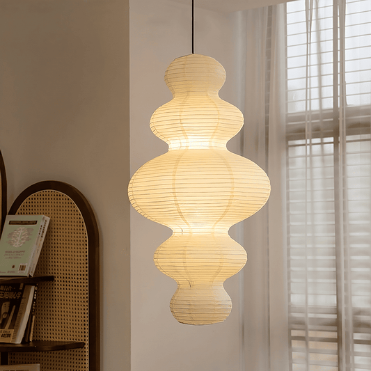 Large Akari Juni washi paper pendant lamp glowing in a minimalist Japandi living room with warm 3000K light.