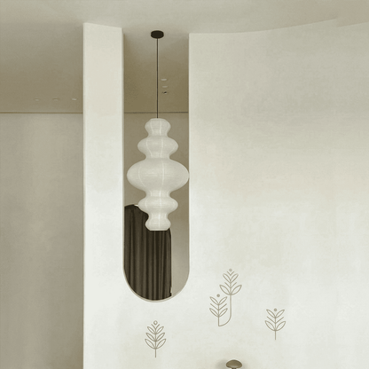 Large Akari Juni washi paper pendant lamp glowing in a minimalist Japandi living room with warm 3000K light.