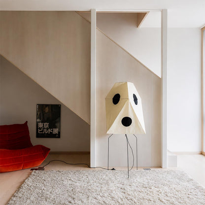 Sculptural geometric paper floor lamp under a staircase in a modern minimalist home.