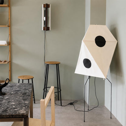 Unique geometric paper floor standing lamp in an industrial style studio with high wooden stool.