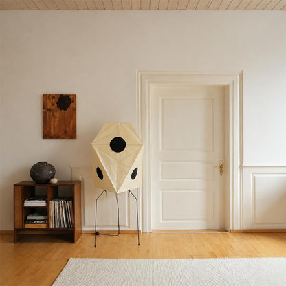 Geometric Wabi-Sabi paper floor lamp standing next to a classic white door and dark wooden cabinet.