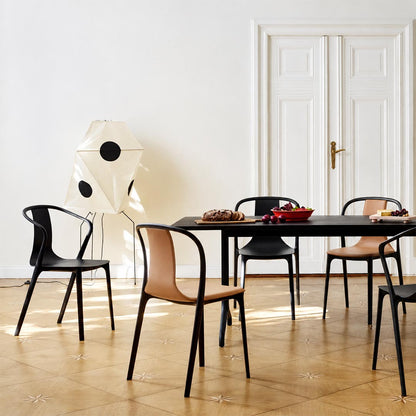 Sculptural paper floor lamp casting light over a dining area with black and wooden chairs.