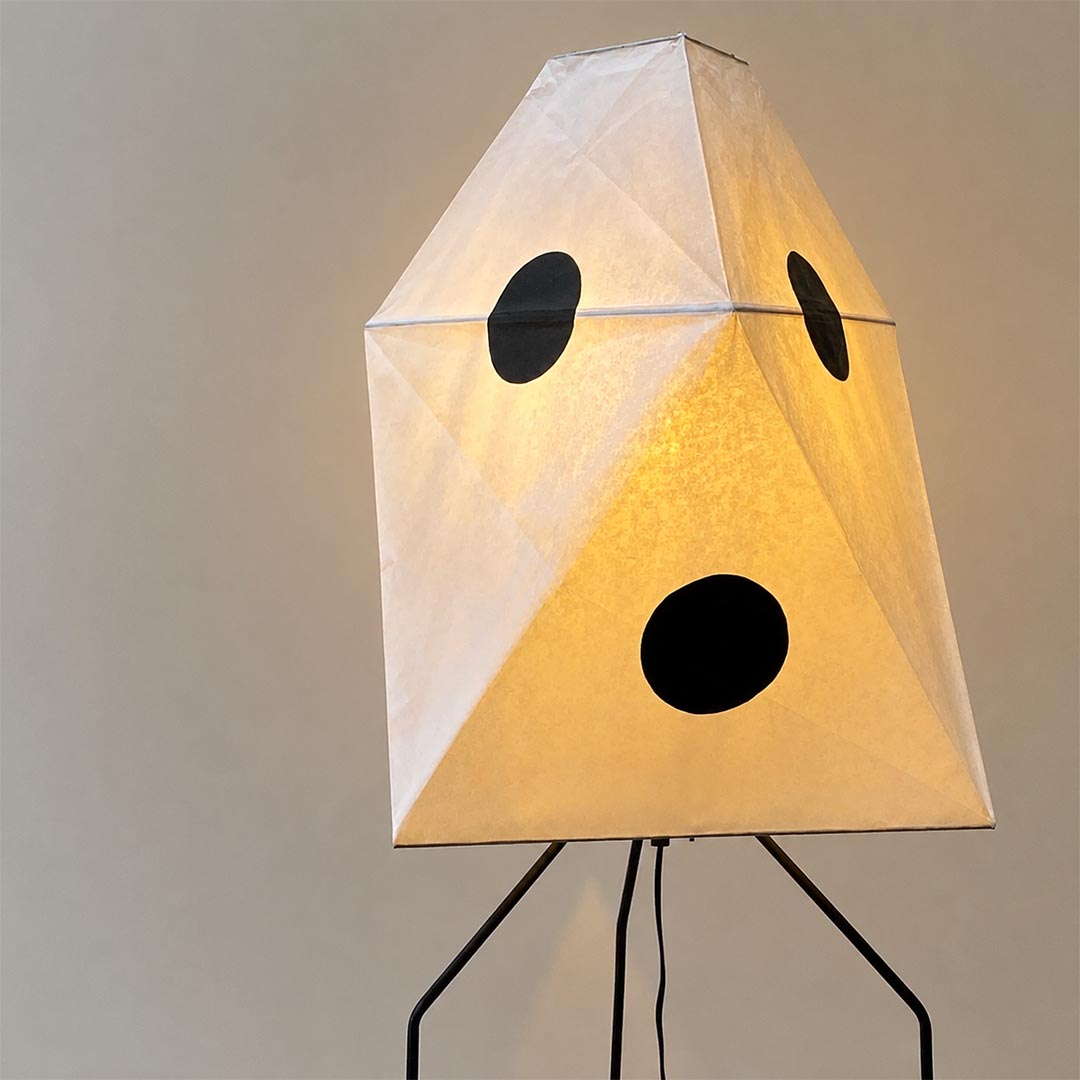 Warm lit geometric paper shade floor lamp featuring a sculptural multi-faceted paper lantern design