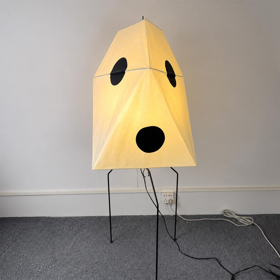 Sculptural paper floor standing light emitting a soft warm ambient glow against a neutral wall background.