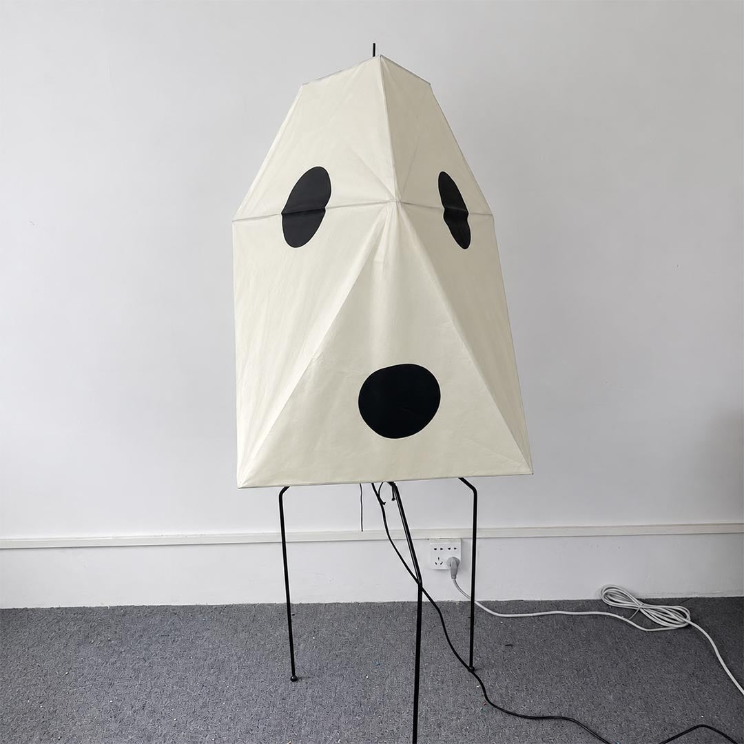 Geometric Wabi-Sabi paper lantern floor lamp with a tripodal metal base in a clean white space.