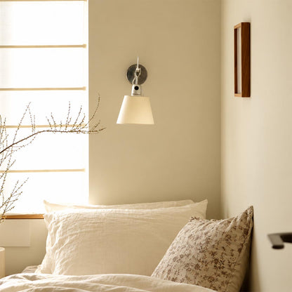 Ardsley swing-arm brass wall sconce mounted as a bedside reading light above cozy white bedding.