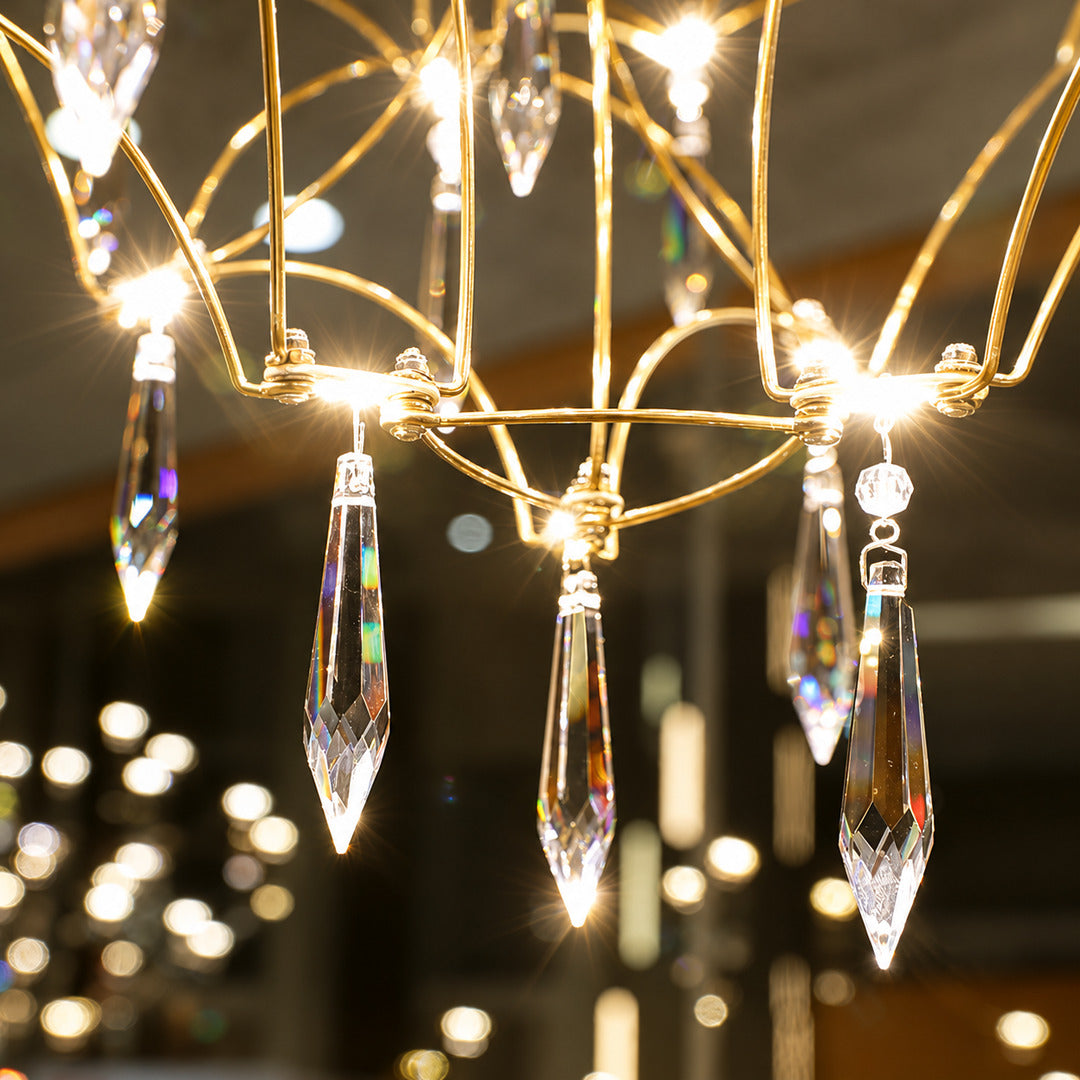 Warm light refracting through the teardrop crystals of the Astra chandelier scattering glints on the walls